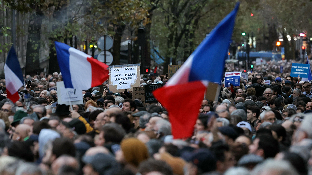 Protesters march waving flags of France and holding a banner which reads as "We said Never Again" as they participate in a march against anti-Semitism in Paris, on November 12, 2023. Tens of thousands are expected to march Sunday in Paris against anti-Semitism amid bickering by political parties over who should take part and a surge in anti-Semitic incidents across France. Tensions have been rising in the French capital, home to large Jewish and Muslim communities, in the wake of the October 7 attack by Palestinian militant group Hamas on Israel, followed by a month of Israeli bombardment of the Gaza Strip. France has recorded nearly 1250 anti-Semitic acts since the attack. National Assembly speaker Yael Braun-Pivet and Gerard Larcher, the Senate speaker, called on November 7 for a "general mobilisation" at the march against the upsurge in anti-Semitism. (Photo by Thomas SAMSON / AFP) (Photo by THOMAS SAMSON/AFP via Getty Images)
